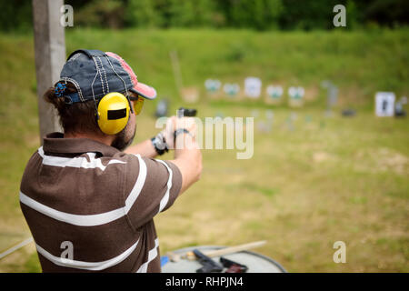 Mann schießt auf einen Schießstand. Männliche, die Pistole an den Schießplatz. Aktive Freizeit. Stockfoto