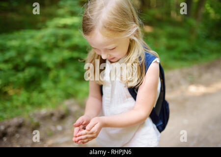 Adorable kleine Mädchen auffällig wenig babyfrogs auf schönen Sommertag im Wald. Stockfoto