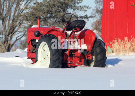 Roter Traktor in tiefem Schnee Stockfoto
