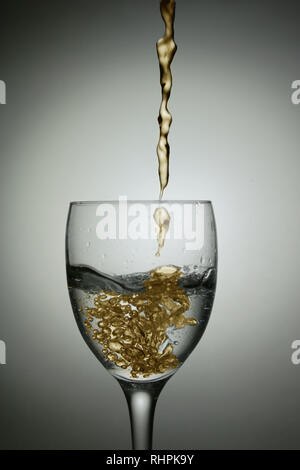 Öl gießen in wineglass Wasser spritzen Fotos Stockfoto