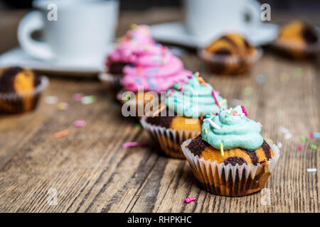 Chocolate Cupcake mit farbigen Rosa und grün Creme auf Holz Tisch Stockfoto