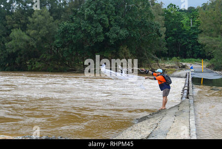 Junge Mann in dem Wirbel aus einem überfluteten Brücke über den Barron River während einer schweren Monsunregen, Cairns, Far North Queensland, FNQ, QLD, Austra Stockfoto