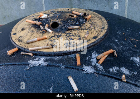 Öffentliche Aschenbecher mit Zigarettenkippen am Eingang zur Einkaufspassage. Stockfoto