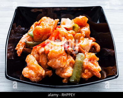 Die koreanische Küche - Rühren - gebratene Garnelen mit Cashew Nüssen und Gemüse in süß-saurer Soße (Garnelen Combo) in Schwarz Schüssel Nahaufnahme Stockfoto