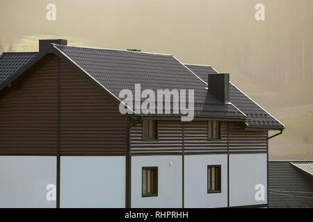 Neue schöne weiße und braune zweistöckiges Ferienhaus mit Schindeldach im ökologischen Bereich auf nebligen Wald und Hügel Hintergrund auf sonnigen Sommertag. Auch maintai Stockfoto