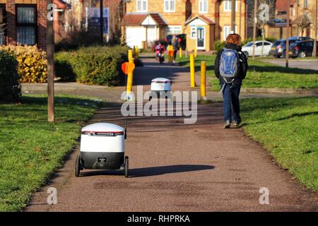 Fußgänger gehen Sie über Ihren Alltag als Starship autonomen Technologien Roboter routine Lebensmittellieferung rund um Milton Keynes. Stockfoto