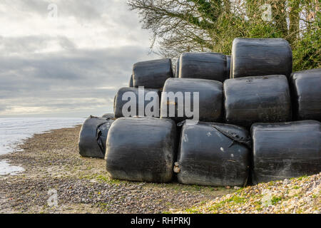 Im Winter gestapelte Heuballen, die zum Schutz mit schwarzem Kunststoff bedeckt sind, Hampshire, England, Großbritannien Stockfoto