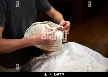 Client mit einem Handtuch vor dem Rasieren in Friseur Stockfoto