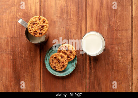 Ein Foto von Chocolate Chip Cookies auf einer dunklen Holzmöbeln im Landhausstil Hintergrund mit Milch und Kopie Raum Stockfoto
