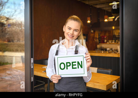Portrait von lächelnden Eigentümer stehen im Restaurant Tür Holding"-Schild, junge Frau Unternehmer bei Eingang von neuen kleinen Familie busines Schiefen Stockfoto