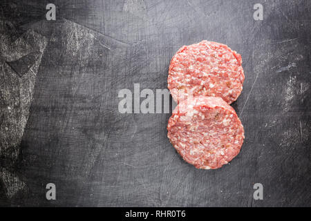 Frische rohe Prime Black Angus Beef Burger Pastetchen auf schwarzem Hintergrund. Ansicht von oben. Stockfoto