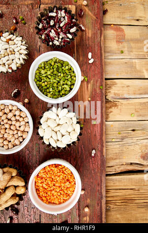 Sammlung von Bohnen und Hülsenfrüchte red türkische Linsen, Kichererbsen, Bohnen, Erdnüsse, Erbsen, kanadische Linsen auf hölzernen Tisch. Schalen mit verschiedenen Linsen. Stockfoto