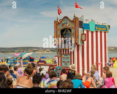 Ein Kasperletheater auf dem Sand von Weymouth, Dorset, England. Eins von nur zwei aktive Entertainer wie in 2018. Stockfoto