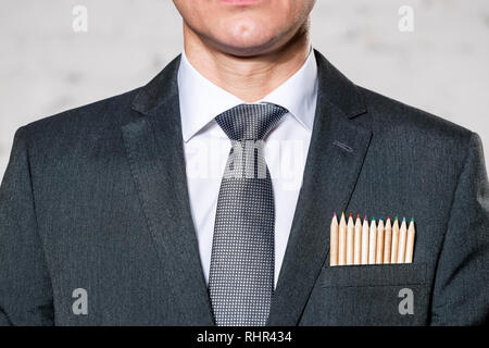 Mittelteil der Geschäftsmann mit Buntstiften in der Tasche gegen die Wand Stockfoto