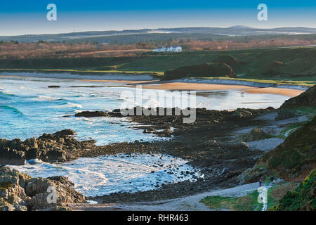 CULLEN BAY Küste von Moray in Schottland Winter mit Schnee auf den Hügeln CULLEN BAY HOTEL MIT BLICK AUF DEN STRAND UND die Spaziergänger Stockfoto