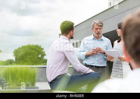 Fachleute diskutieren über Dokumente mit Kollegen im Büro Terrasse Stockfoto