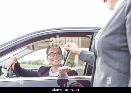 Frau, die Schlüssel zu lächeln, Geschäftsfrau im Auto. Stockfoto