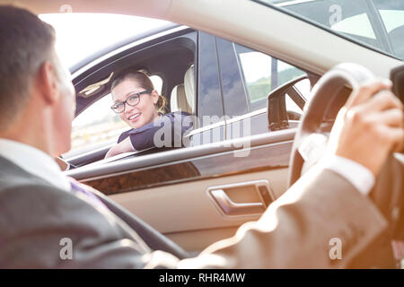 Lächelnd Geschäftsfrau im Gespräch mit Executive beim Sitzen im Auto. Stockfoto