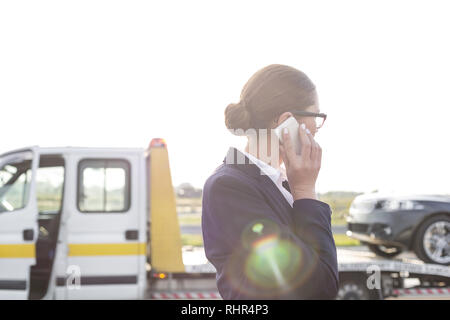 Business Professional am Telefon sprechen, während Abschleppwagen bis Ihr Auto Kommissionierung Stockfoto