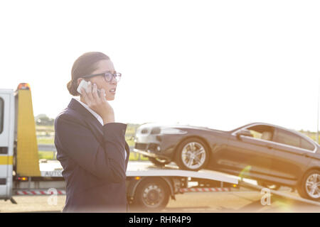 Business Professional am Telefon sprechen, während Abschleppwagen bis Ihr Auto Kommissionierung Stockfoto