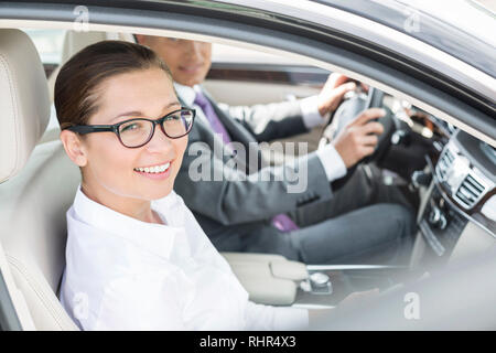 Portrait von Lächeln, Geschäftsfrau, Sitzen mit Kollegen im Auto. Stockfoto