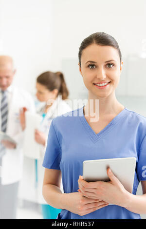 Portrait von Krankenschwester mit digitalen Tablette gegen Ärzte an der Klinik Stockfoto