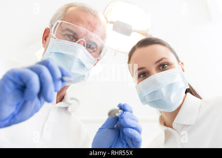 Low Angle Portrait von männlichen und weiblichen Zahnärzte tragen Masken an den zahnmedizinischen Klinik Stockfoto