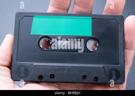 Audio Kassette mit Platz für Text Eintrag auf der Handfläche. Kassette ohne Beschreibung. Der dunkle Hintergrund. Stockfoto