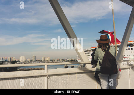 Eine junge Frau in einem braunen Hut boards der Carnival Inspiration Kreuzfahrtschiff in Long Beach, Kalifornien, USA, über die Gangway auf das Boot an einem sonnigen Tag Stockfoto