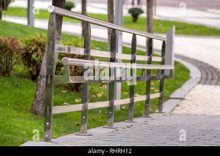 Metallzaun Konstruktion aus glänzenden nassen Edelstahl Rohre entlang der Straße Highway auf der Kopie Raum Hintergrund von grünem Gras Landschaft und Weiße verschwommene Stockfoto