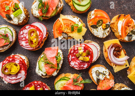 Verschiedene spanische Tapas mit Fisch, Wurst, Käse und Gemüse. Dunkler Hintergrund, flach. Stockfoto