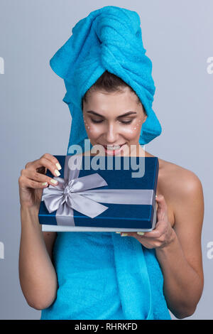 Schöne junge Frau nach der Dusche mit Handtuch auf dem Kopf und Creme im Gesicht öffnen Beauty Urlaub Geschenk Stockfoto