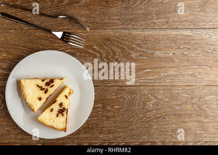 Hausgemachter Käsekuchen mit Schokolade Chips auf einem weißen Teller. Holz- Hintergrund, Ansicht von oben und kopieren Raum Stockfoto