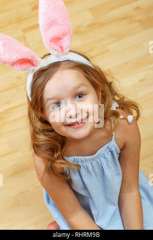 Süßes kleines Kind Mädchen mit Hasenohren sitzt auf dem Boden. Frohe Ostern Stockfoto