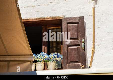 Obere Wohnung im Dorf Lindos mit Seide Blumen in spitze Töpfe auf der Fensterbank. Stockfoto