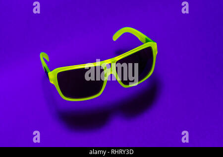 Helle grüne Farbe Sonnenbrille in der Luft. Grüne, die in der Luft schweben Sonnenbrille auf lila Hintergrund. Untere Schatten unterhalb der Gläser. Minimalismus summ Stockfoto