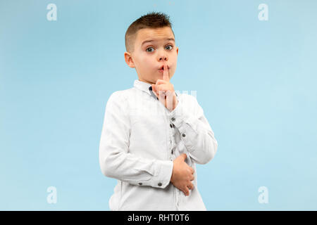 Geheimnis, Klatsch-Konzept. Jugendlich junge Flüstern ein Geheimnis hinter seiner Hand. Kind isoliert auf trendigen Blau studio Hintergrund. Menschliche Gefühle, Mimik Konzept. Stockfoto