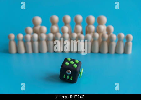 Menge Ruhe Konzept. Antwort wie die Menge zu beruhigen. Fidget Cube Druckhelfer und Holzfiguren auf einem blauen Hintergrund Stockfoto