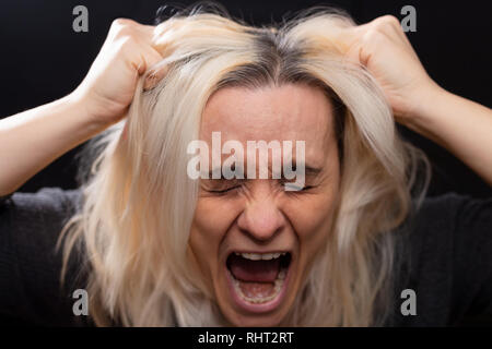 Blonde woman screaming and pulling her hair with her hands Stockfoto