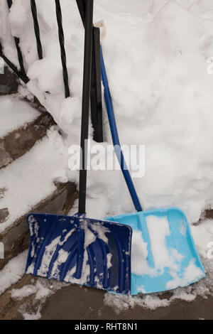 Zwei Schnee schaufeln Lean gegen einen schmiedeeisernen Geländer auf einem schneebedeckten Treppe. Stockfoto