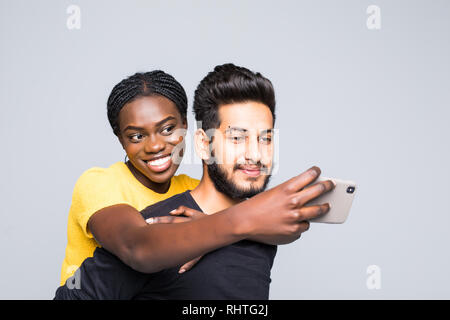 Portrait einer jungen gemischtrassiges Paar beim piggyback Ride auf dem grauen Hintergrund isoliert Stockfoto