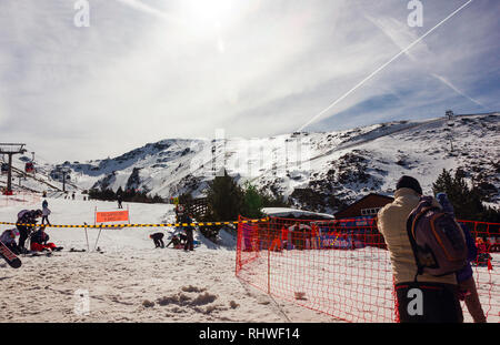 Verschneite Skipisten im Skigebiet Pradollano in der Sierra Nevada in Spanien mit Menschen Skifahren Stockfoto