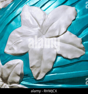 Im asiatischen Stil White Orchid Flower, Skulpturen aus Beton, die von einem Aqua farbig lackierten Hintergrund umgeben. Es hat einen quadratischen Format. Stockfoto
