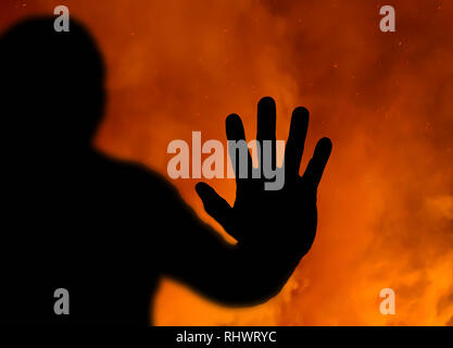 Zusammenfassung einer Silhouette der Hand gedrückt, bis in einem Fenster mit einem Feuer im Hintergrund tobt. Konzept im Feuer gefangen. Stockfoto