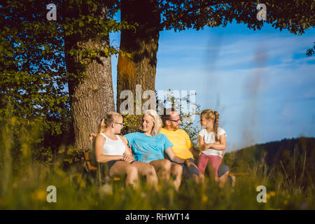 Familie ruht auf der Bank bei einem langen Spaziergang im Sommer Stockfoto