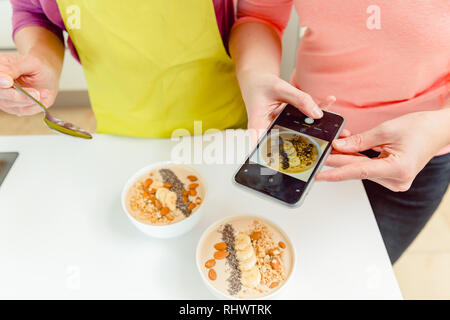 Weibliche nimmt pic von gesunden Müsli Schalen durch Handy Stockfoto