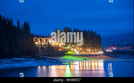 Panorama Blick auf ein Dorf am See in der dospat Dam, Bulgarien in mystischer Dämmerung während der Blauen Stunde am Morgen einen schönen kalten nebligen Tag im Winter. Stockfoto