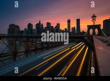 Eine longexposure Erfassung bei Brooklyn Bridge mit lighttrails der vorbeifahrenden Autos und der weltberühmte Silhouette von Manhattan Stockfoto