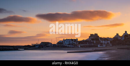 Lyme Regis, Dorset, Großbritannien. 4. Februar 2019. UK Wetter: Der Himmel leuchtet orange, wie die Sonne über dem Meer Gebäude und der Cobb in Lyme Regis nach einem Tag Regen und starkem Wind. Credit: Celia McMahon/Alamy leben Nachrichten Stockfoto