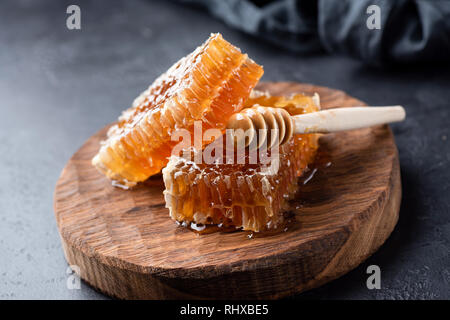 Waben und Honig Pendelarm auf Holzbrett. Frische Honig. Schwarz konkreten Hintergrund Stockfoto